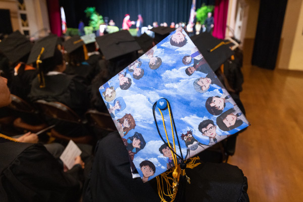 Decorated graduate cap with blue sky and little humans