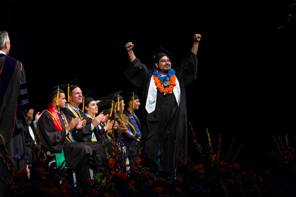 Graduate walking across stage with raised arms