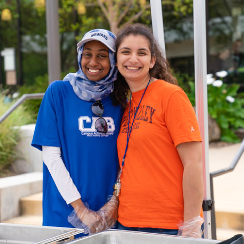Two female students smiling during outdoor campus event