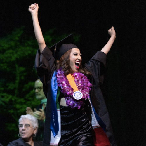 Female graduate celebrating with raised arms