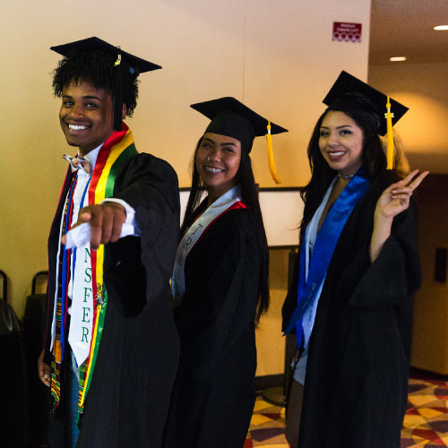 Three graduates waving at camera