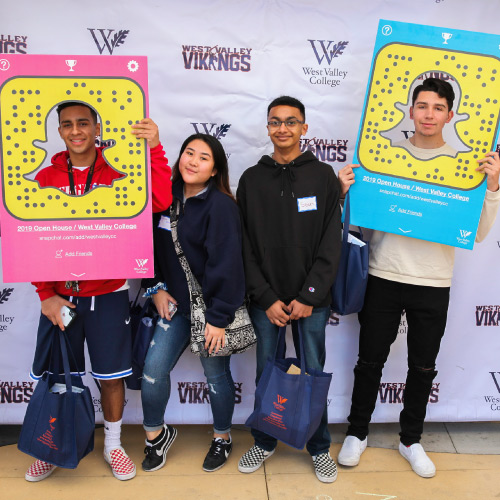 Students with Snapchat props in front of step and repeat